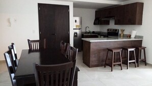 Una cocina moderna con armarios de madera oscura, un refrigerador de acero inoxidable y una isla central con taburetes.