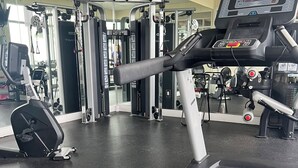 Ein Fitnessraum mit Trainingsgeräten, Laufband und Spiegelwand.