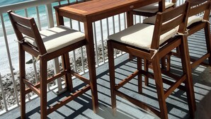 Ein Holztisch und Stühle auf einem Balkon mit Blick aufs Meer.