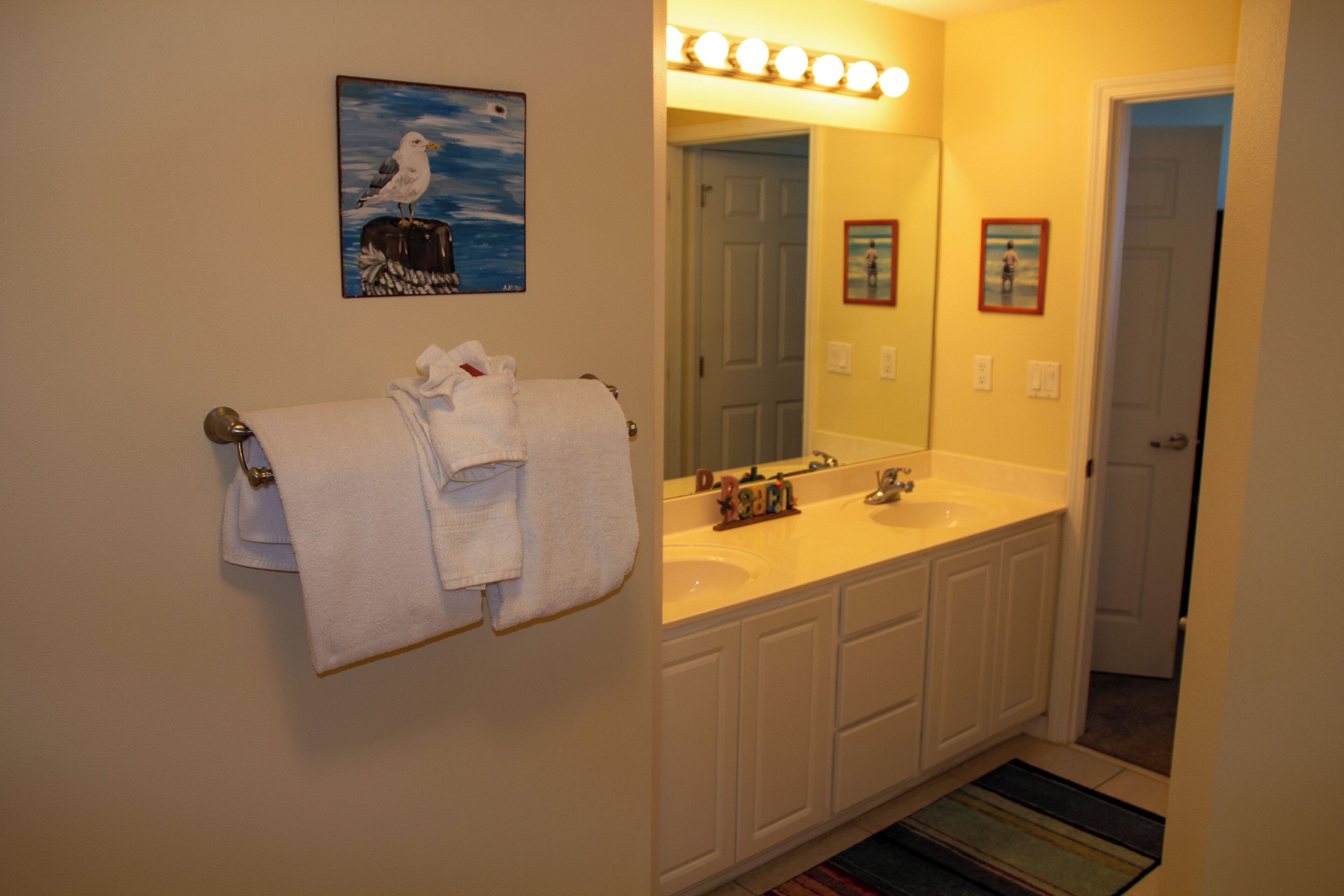 A bathroom with a white sink, mirror, and towel rack.