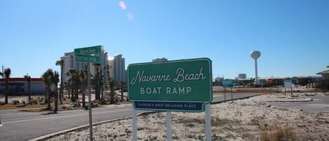 Un panneau indiquant l’accès à la rampe de mise à l’eau pour bateaux de Navarre Beach, avec un ciel dégagé et des palmiers en arrière-plan.