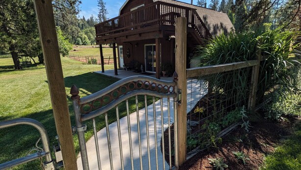 A wooden cabin with a porch and a metal gate. - Serene Farmhouse with Pond & Forest View in Beautiful Grass Valley (Grass Valley)