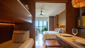 Habitación de hotel con dos camas, un banco de madera, una mesita y vistas al exterior.