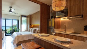 A modern kitchen with wooden cabinets, a built-in microwave, and a large window overlooking a scenic view. - Beautiful beachfront Studio, Zantamar 304 (Cruz de Huanacaxtle)