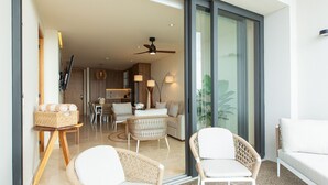 A modern living room with wicker furniture, a white sofa, and a dining area with a table and chairs. - Beachfront Condo, Zantamar 205 (Cruz de Huanacaxtle)