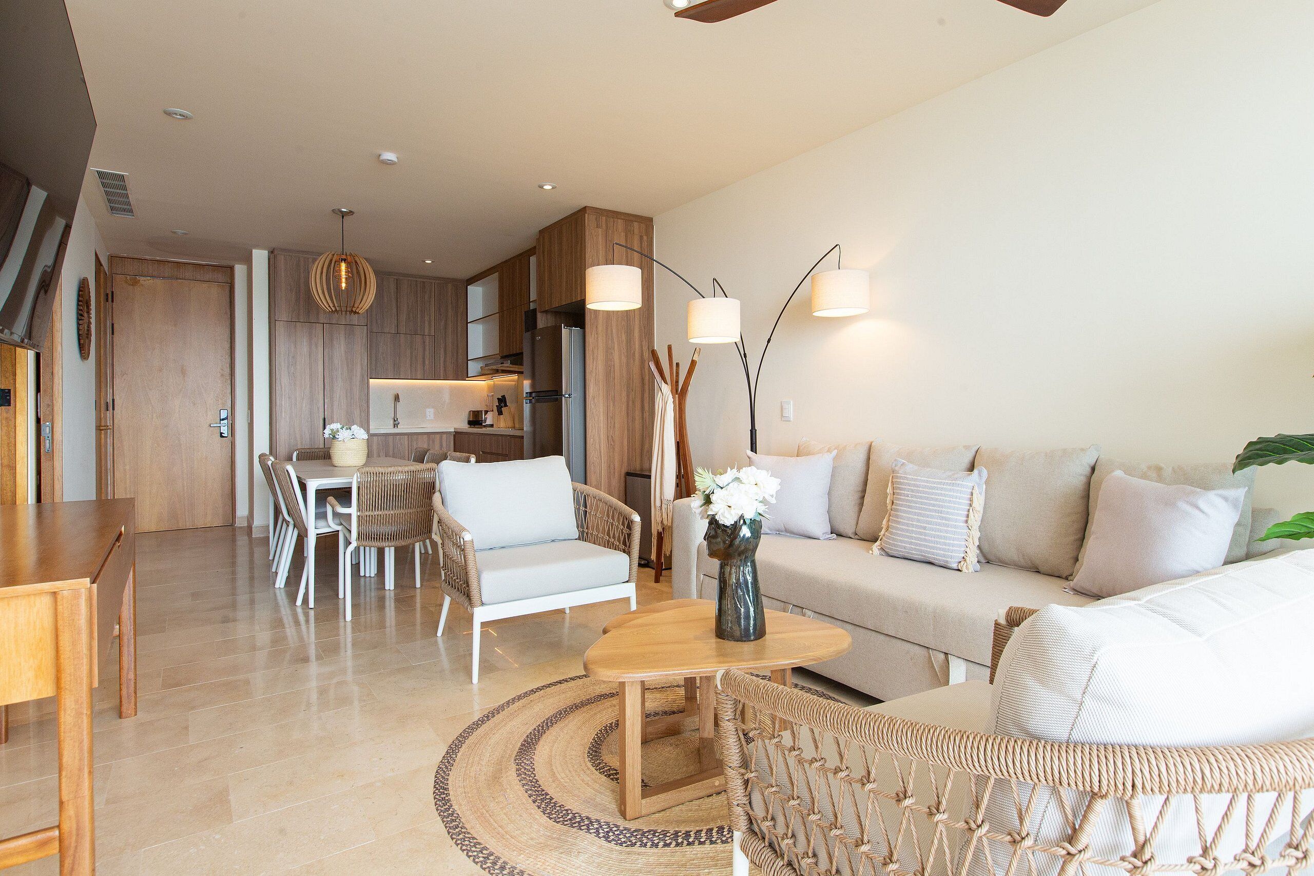 Una sala de estar moderna con sofá, sillones, una mesa de centro y un comedor con mesa y sillas.