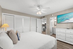 A bedroom with a bed, a ceiling fan, a TV, and a dresser.