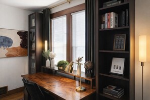 A study room with a wooden desk, bookshelves, a globe, and a framed book titled 'The ELY'.