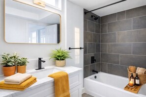 A modern bathroom with a white vanity, a black shower, and a large mirror.