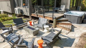 Una terrazza esterna con poltrone Adirondack, un braciere e una vasca idromassaggio.
