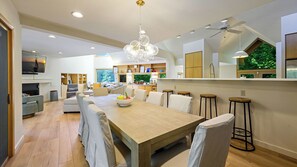 Cozinha moderna com mesa de jantar de madeira, banquetas e um candelabro.