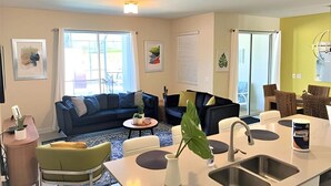 A modern living room with a sofa, coffee table, and dining area.