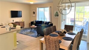A modern living room with a sofa, dining table, and a TV.