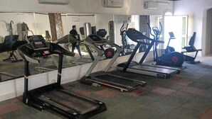 Une salle de sport équipée de tapis de course, de vélos d’appartement et d’autres appareils de musculation.