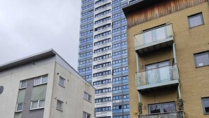 A multi-story building with a mix of residential and commercial spaces, featuring a prominent glass facade and a variety of window styles.