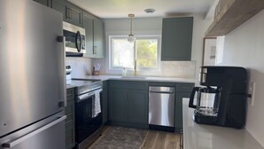Una cocina moderna con electrodomésticos de acero inoxidable, lavavajillas y cafetera.