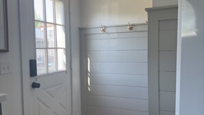 Un pasillo con una puerta blanca, una ventana y una lámpara en el techo.
