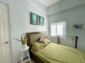 Relax in this serene bedroom with a single bed, potted plant, and framed artworks.