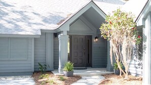 A house with a grey exterior, a dark front door, and a small garden with potted plants and a tree. - Sea Pines! Beach, pool, Harbour Town Golf Links view, sleeps 8 & pet friendly! (Hilton Head Island)