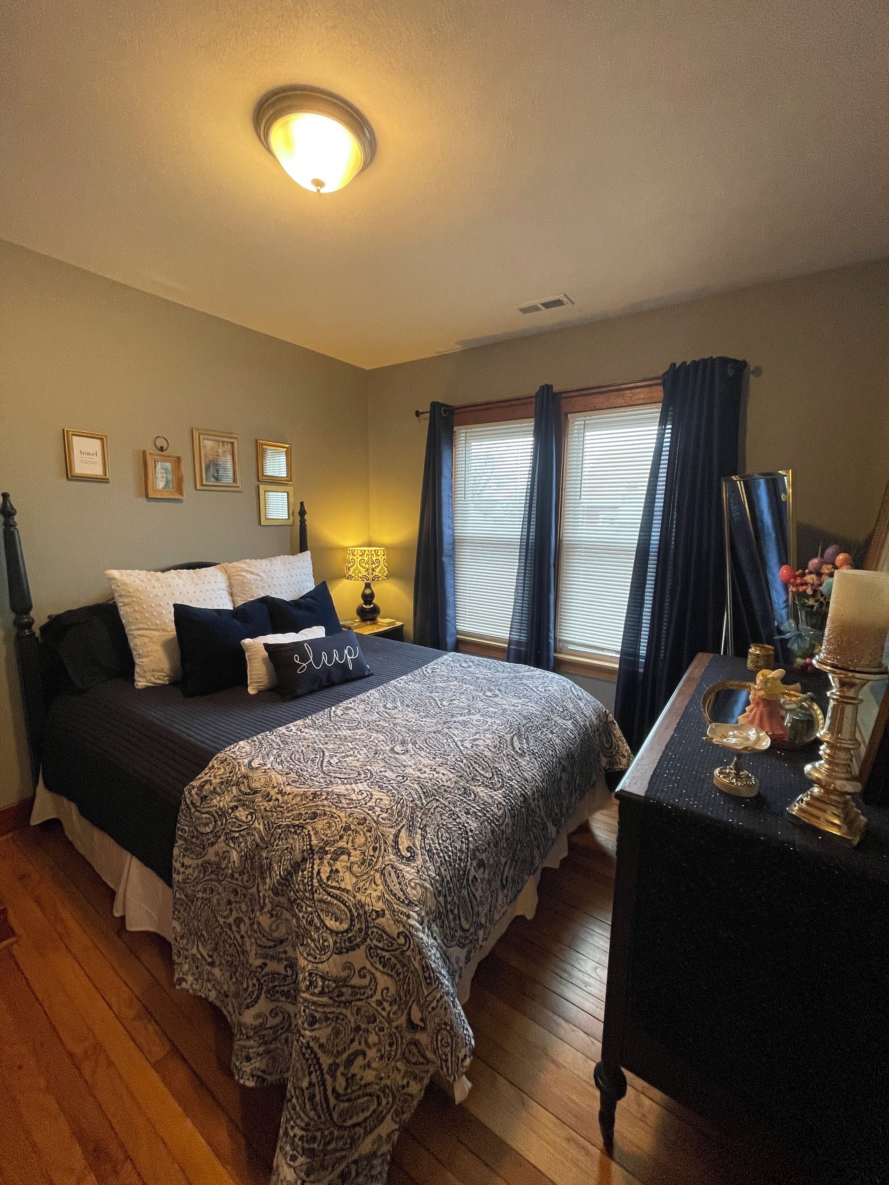 A bedroom with a bed, bedside table, lamp, and window with curtains.