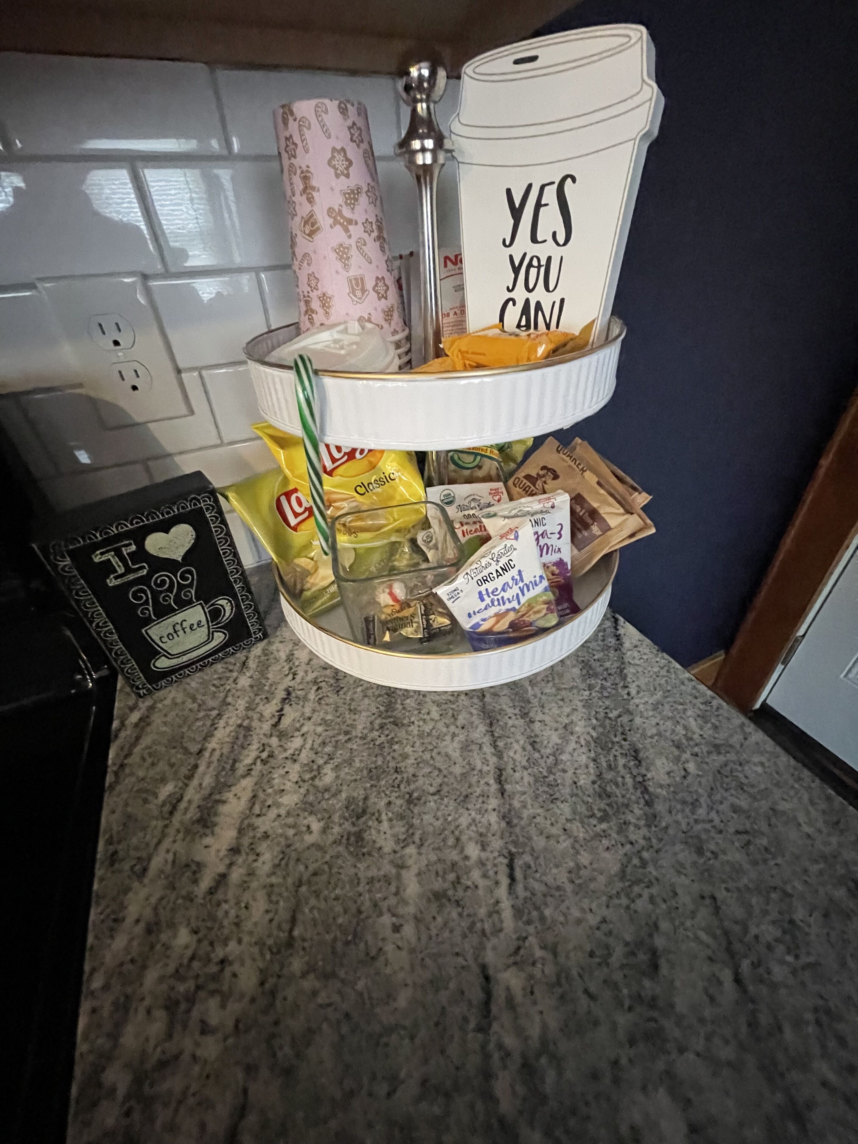 A kitchen counter with a coffee maker, a coffee cup, and various snacks.
