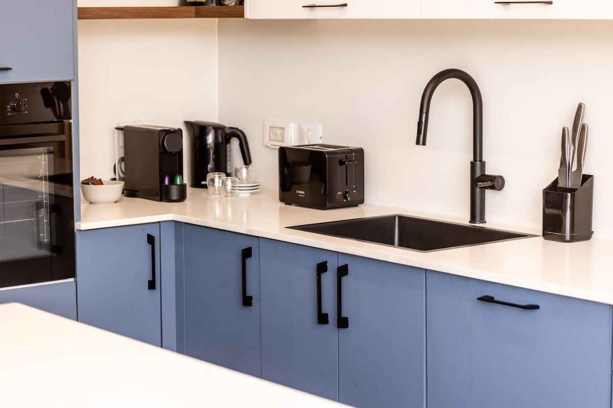 Eine moderne Küche mit einem schwarzen Wasserhahn, einer Kaffeemaschine und einem Toaster.