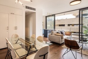 A modern living space with a glass dining table, sofas, and a view of an urban area.