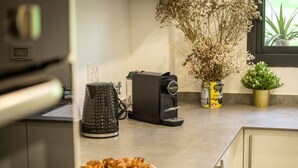 A kitchen with a coffee maker, a kettle, and a plate of food. - Modern 2BR Apartment Near Baháʼí Gardens – Haifa (Haifa)