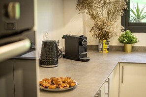 Una cucina con una macchina da caffè, un bollitore e un piatto di cibo.