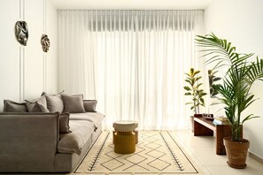 Un salon moderne avec un canapé, un tapis à motifs et une plante en pot.