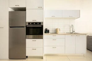 Une cuisine moderne dotée d’appareils électroménagers en acier inoxydable, de meubles blancs et d’un four encastré.