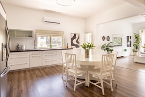 Een moderne keuken met witte kasten, een eettafel met stoelen en een raam dat voor natuurlijk licht zorgt.