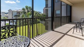 Een balkon met uitzicht op een woonwijk, een houten vloer en een tafel met stoelen.