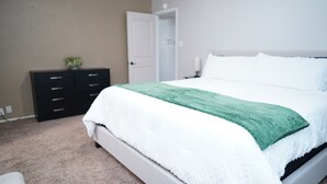 Una camera da letto con un letto, un comodino, una cassettiera e una porta.