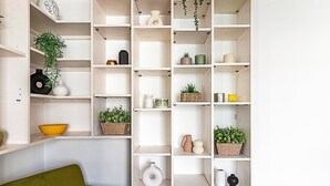 Un intérieur moderne avec des étagères blanches, dont certaines contiennent des plantes et des objets décoratifs.
