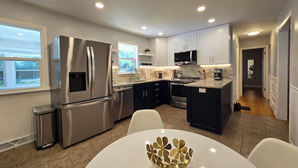 A modern kitchen with stainless steel appliances, white cabinets, and a central island. - Rockford Cascade Getaway (Rockford)