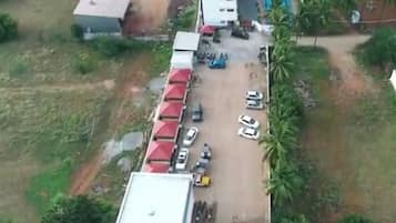 An aerial view of a property with a parking area, buildings, and greenery.