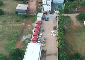 Vista aérea de um terreno com estacionamento, edifícios e áreas verdes.
