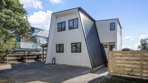 Et moderne hus med to etager, skråt tag, en indhegnet baghave og en belagt indkørsel.
