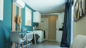 Un salon moderne avec un canapé, un coin repas comprenant des chaises et une table, et une cuisine en arrière-plan.