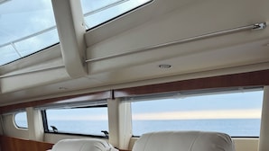 A luxurious cabin with plush white leather seating, a sunroof, and a view of the ocean.