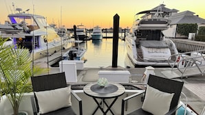A marina with boats docked, a table with two chairs, and a potted plant.