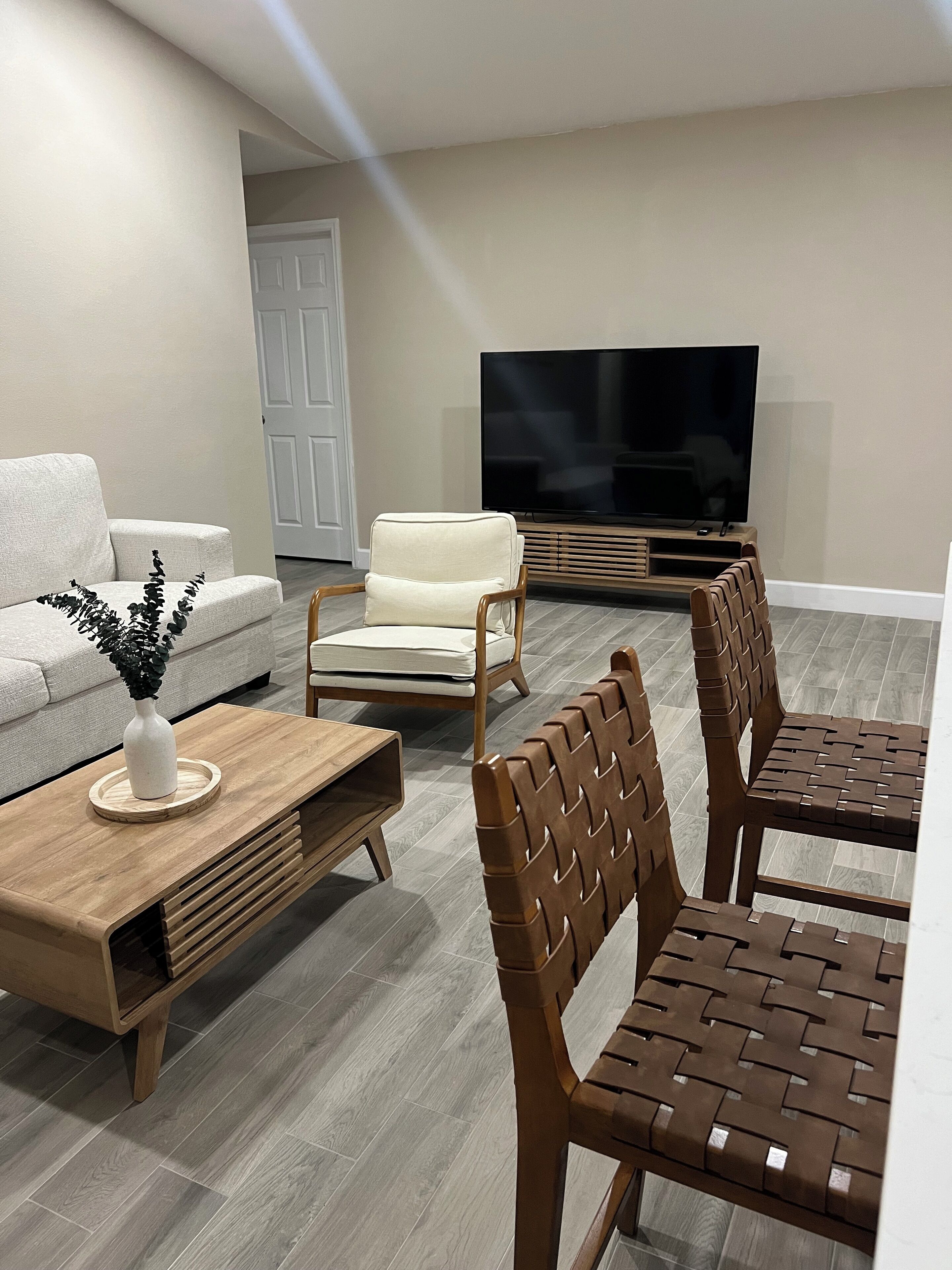 A modern living room with a sofa, two armchairs, a coffee table, and a TV.