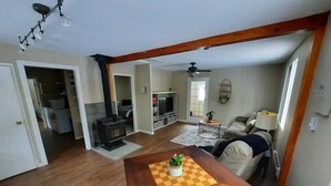 A living room with a wooden table, a sofa, a television, and a ceiling fan. - Cozy 3 bedroom cottage in the woods

 (Salmon Arm)