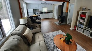 A modern living room with a sofa, a coffee table, and a bookshelf. - Cozy 3 bedroom cottage in the woods

 (Salmon Arm)