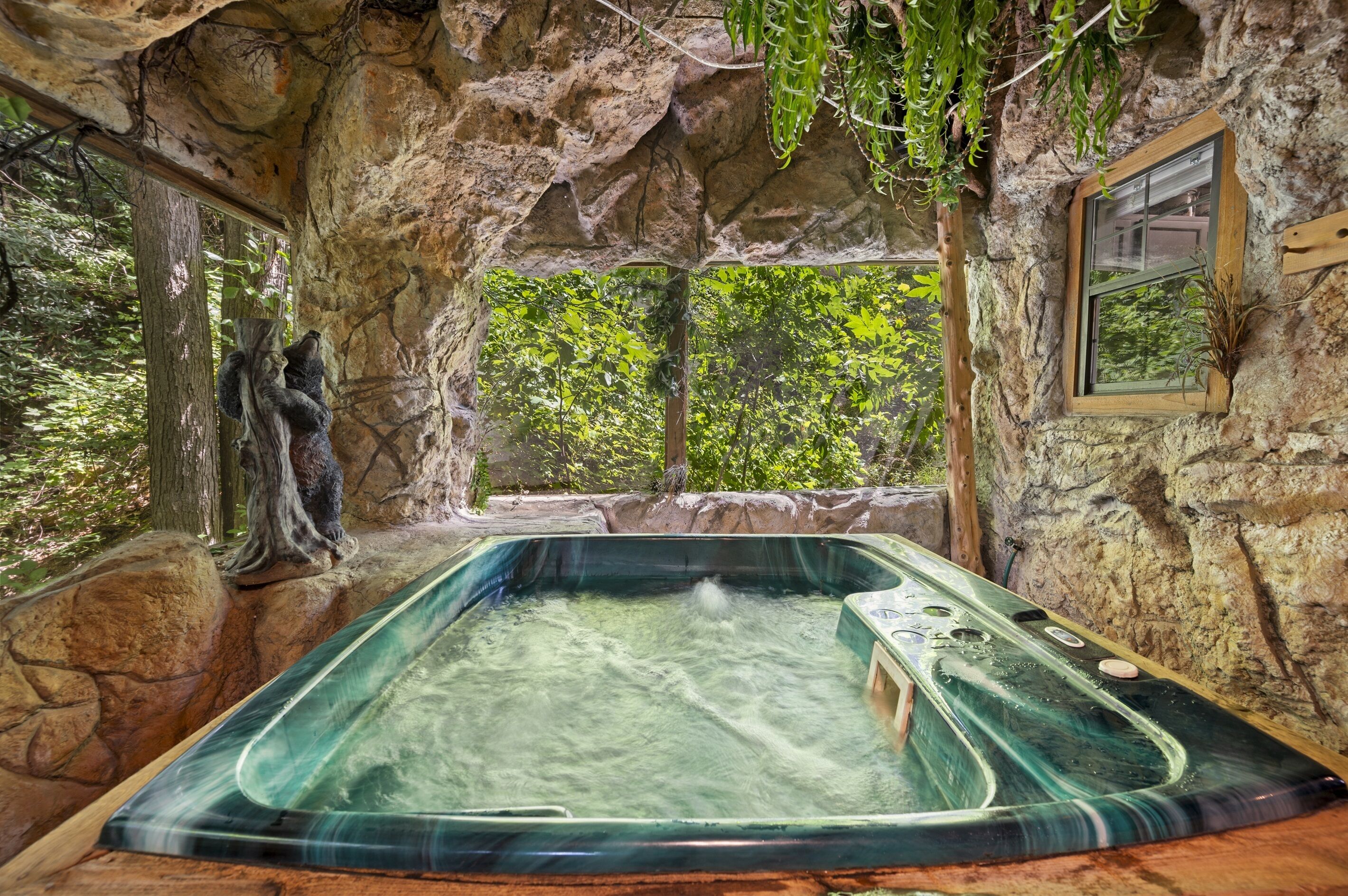 A hot tub in a natural stone setting with a view of trees.