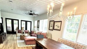 A spacious living room with a wooden dining table, sofas, and a chandelier. - 2 Primary Kings! Screened Porch! EV Charger! (Bay Saint Louis)