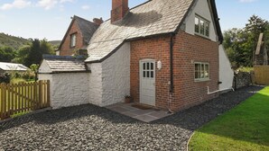 A traditional brick house with a white exterior, a chimney, and a small porch. - A relaxing escape for couples in a cosy old cottage with gorgeous rural views. (Llangollen)