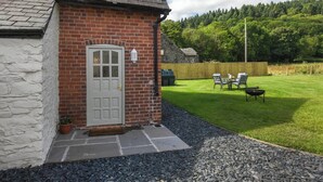 A brick house with a white door, a small garden with a barbecue area, and a stone wall. - A relaxing escape for couples in a cosy old cottage with gorgeous rural views. (Llangollen)