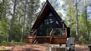 A cabin with a wooden exterior, a deck, and a fire pit area.